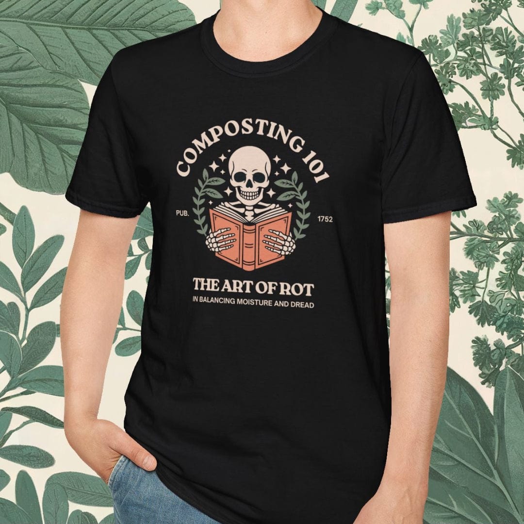 Person wearing a black t-shirt with a graphic design and text, standing against a leafy green background.