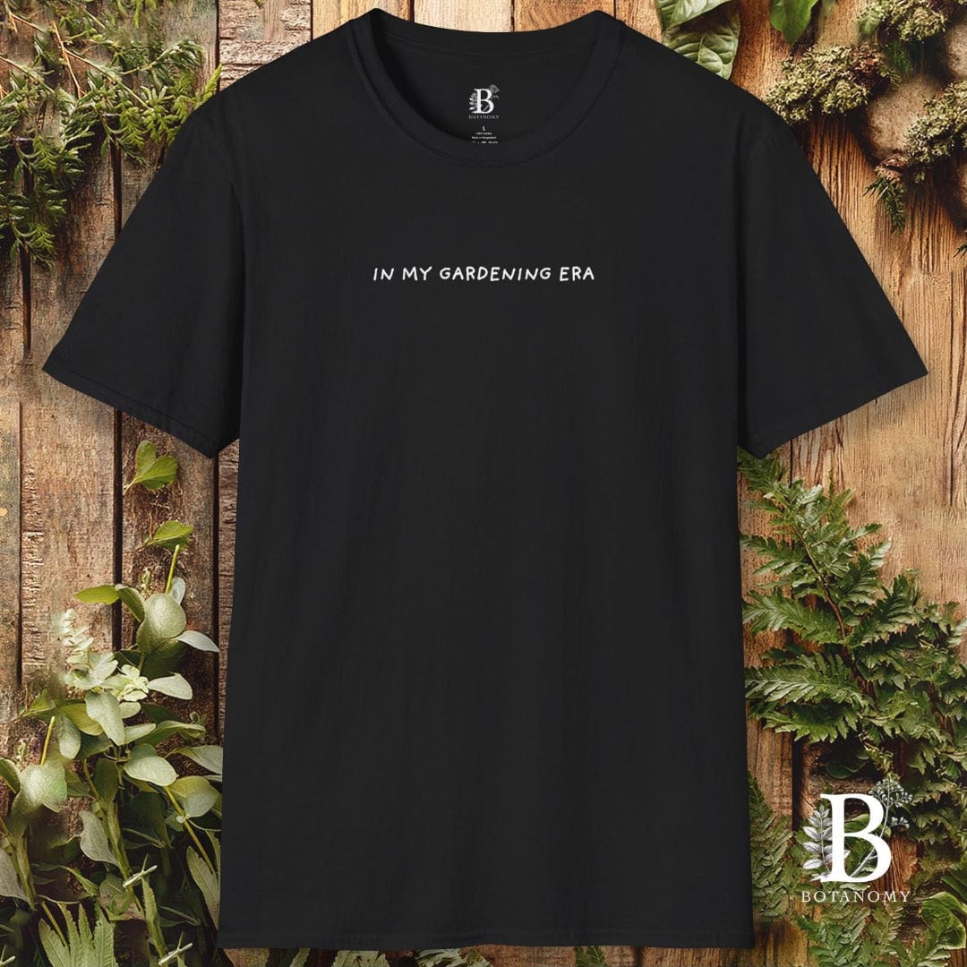 Black t-shirt with 'IN MY GARDENING ERA' text on a wooden background with plants