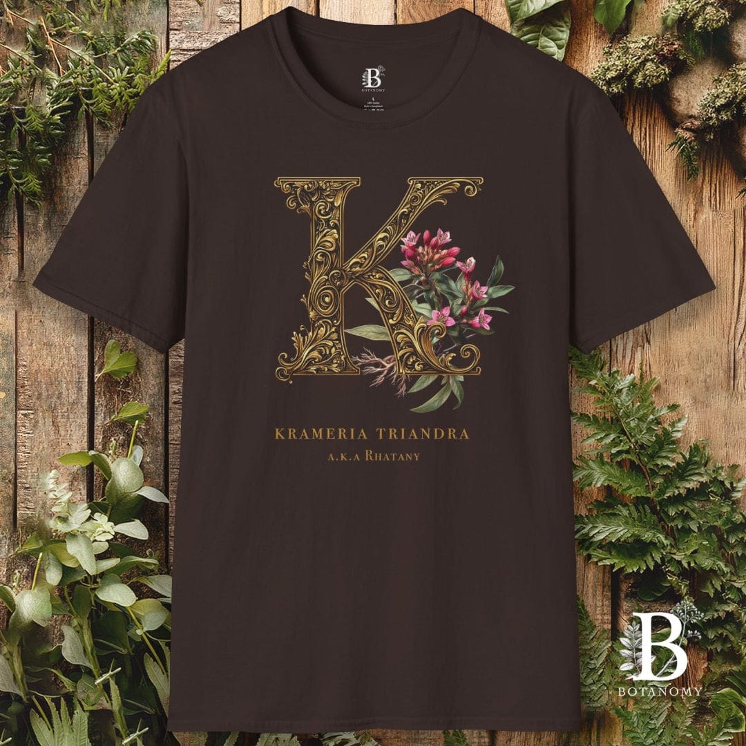 Brown t-shirt with decorative letter 'K' and floral design on a wooden background