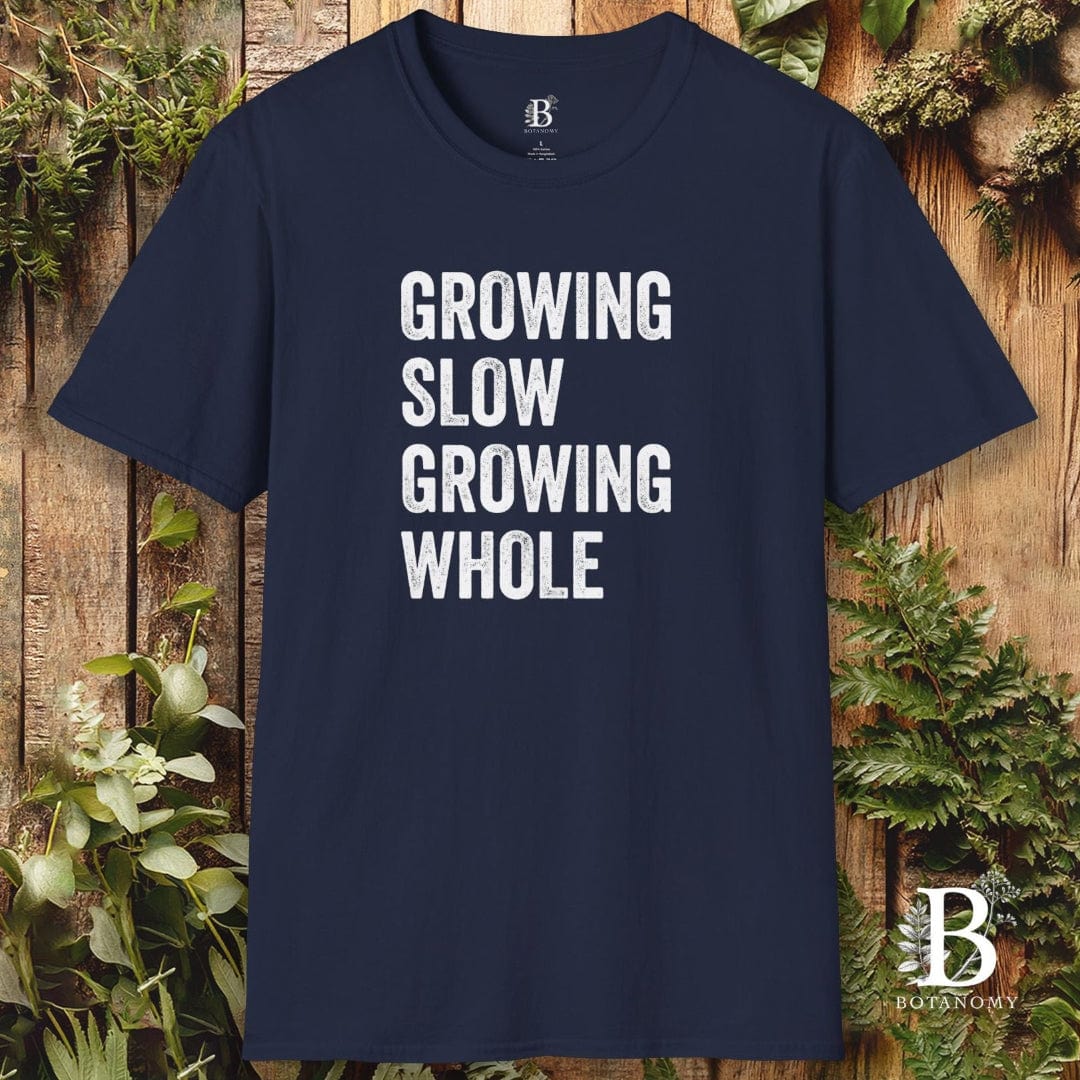 Navy blue t-shirt with 'GROWING SLOW GROWING WHOLE' text on a wooden background with plants.