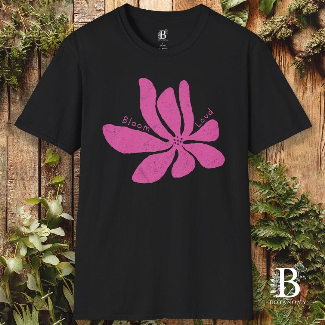 Black t-shirt with a pink flower design and 'Bloom Loud' text on a wooden background.