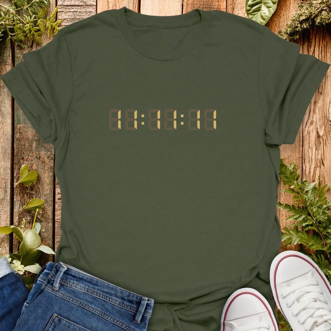 Green t-shirt with a gold digital clock graphic showing 11:11:11 on the chest, styled in a flat-lay with blue jeans, white sneakers, and green plants on a rustic wooden background.