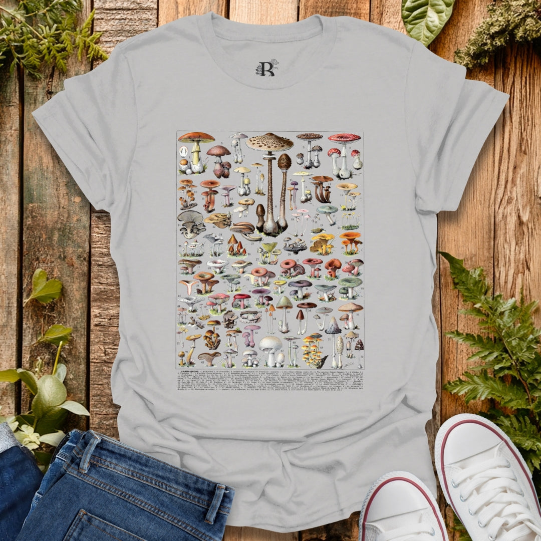 Gray t-shirt with mushroom illustration on a wooden surface with plants.