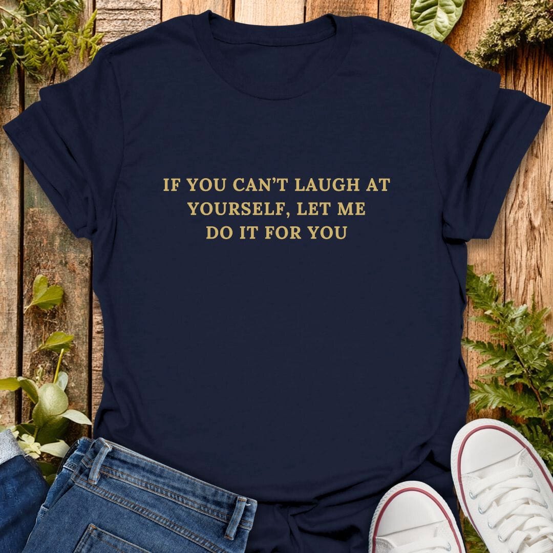 Navy blue t-shirt with text "If you can't laugh at yourself, let me do it for you" on a wooden surface with plants, jeans and sneakers.
