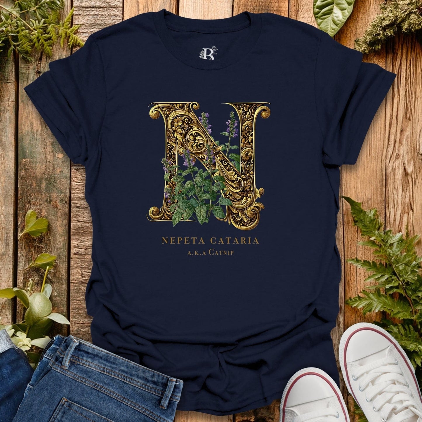 Navy blue t-shirt with ornate letter 'N' design on a wooden surface with plants.