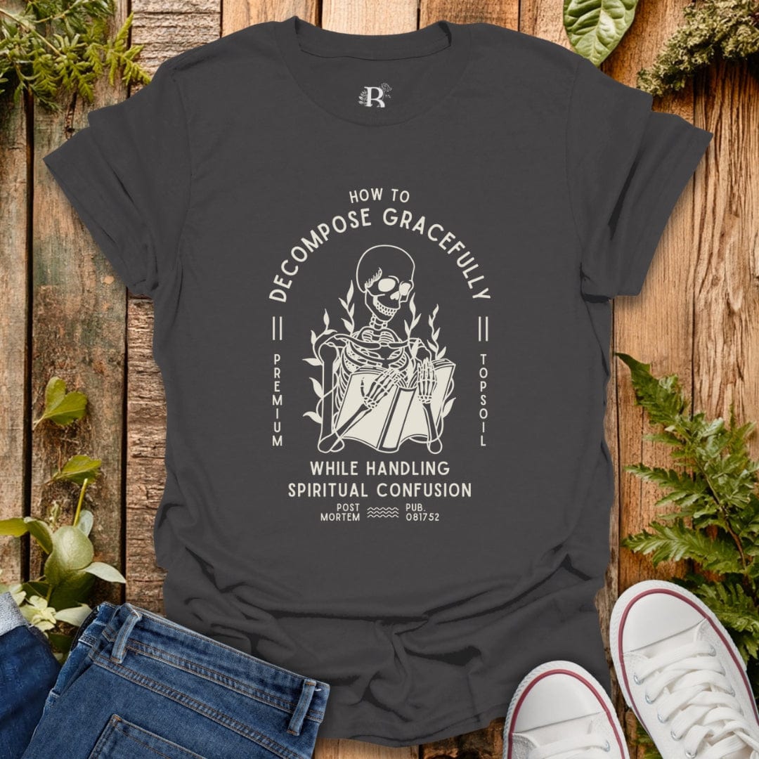 Dark gray t-shirt with skeleton graphic and text on a wooden surface with plants.