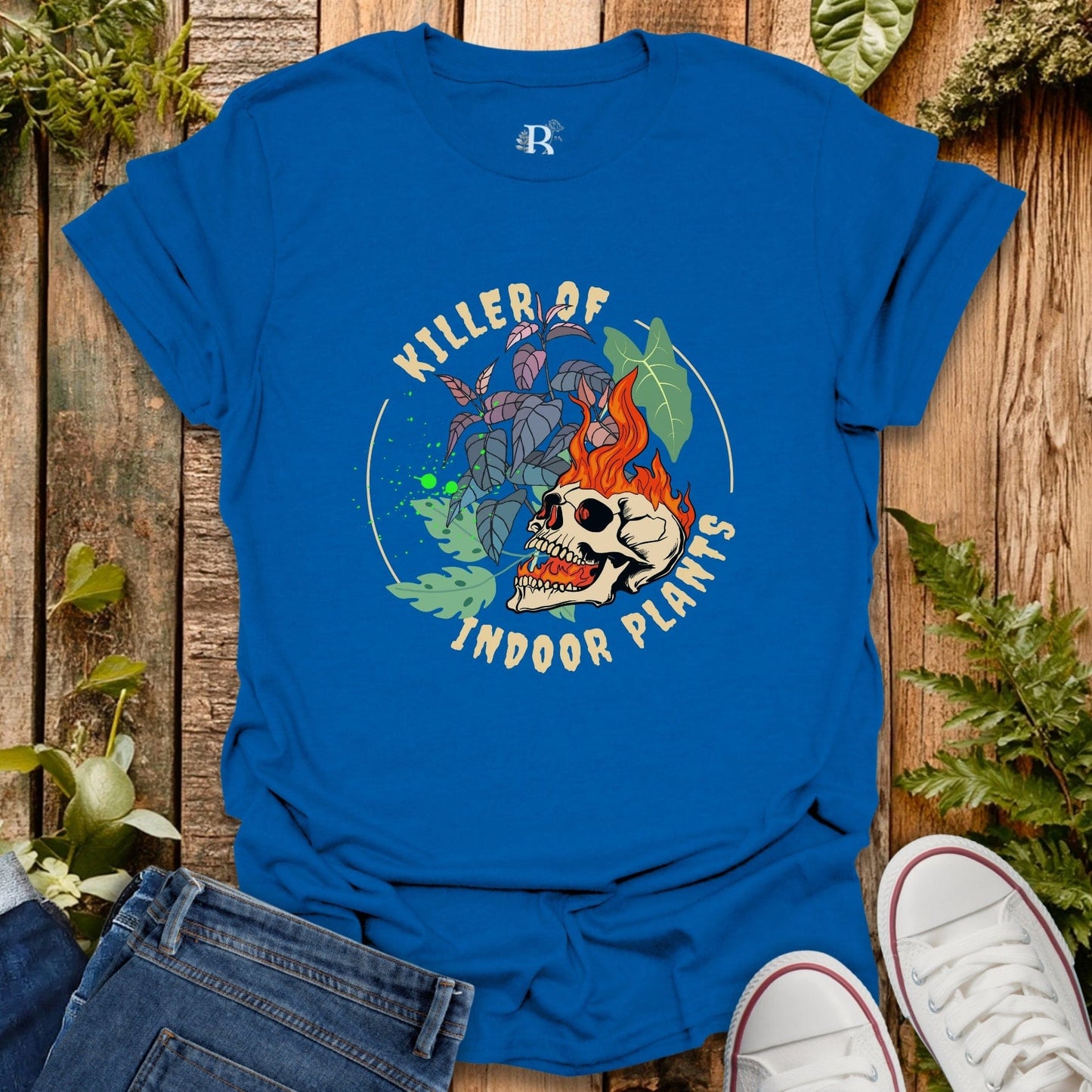Blue t-shirt with graphic design and text on a wooden surface with plants.