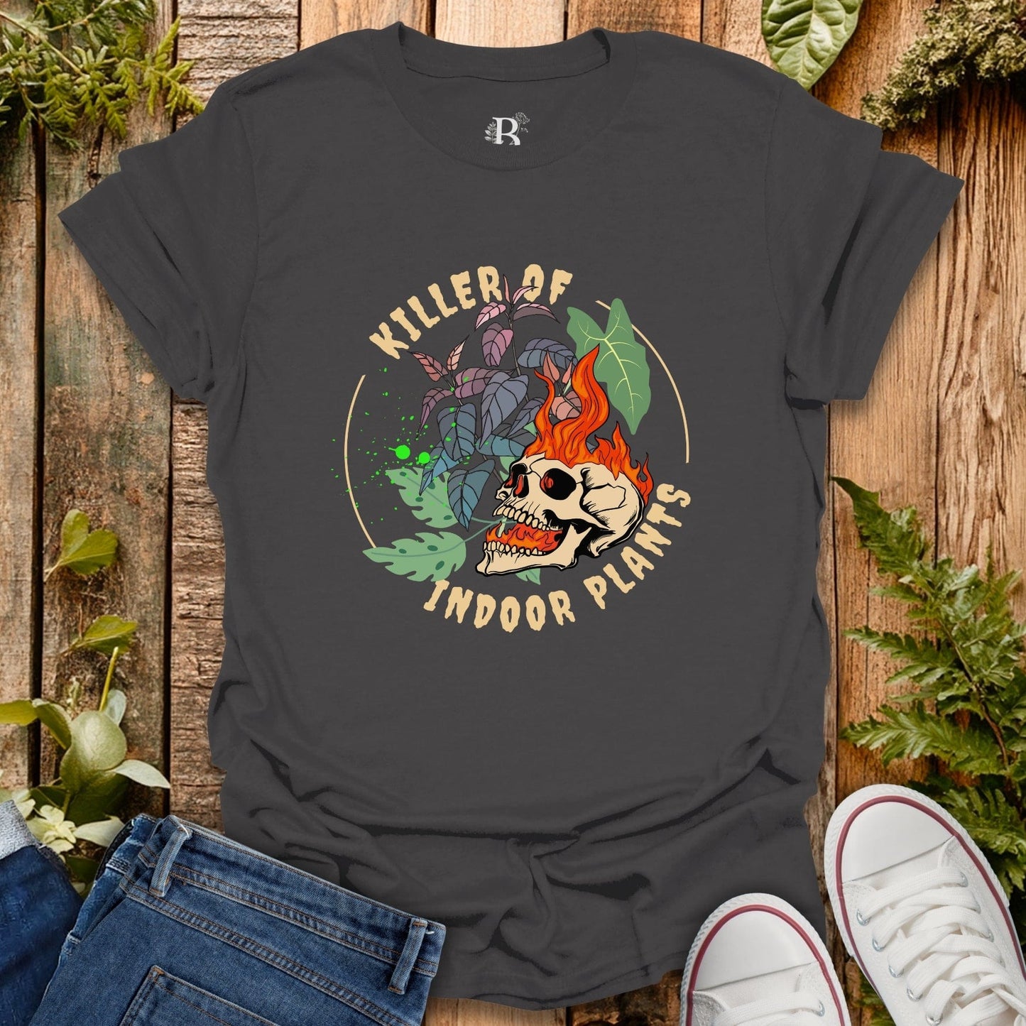 Black t-shirt with skull and plant design on a wooden surface with plants around