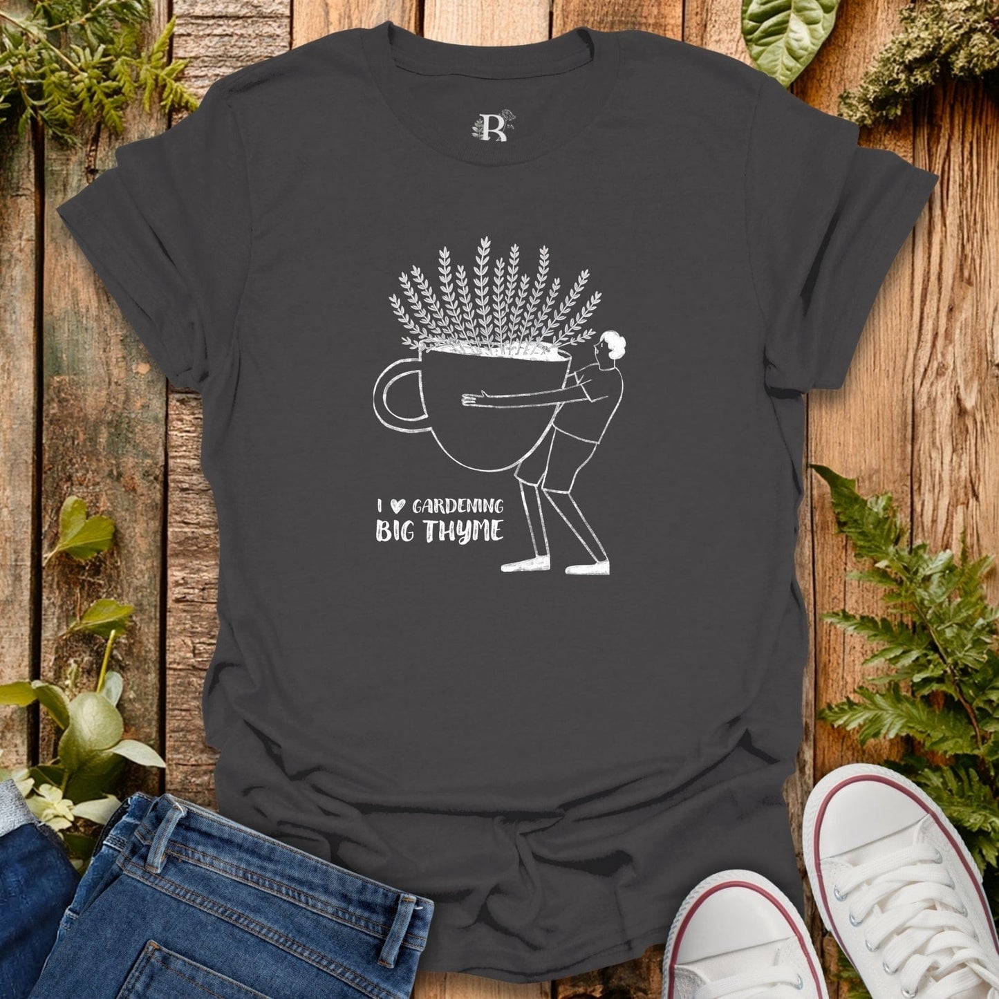 Black t-shirt with white graphic design on a wooden surface with plants