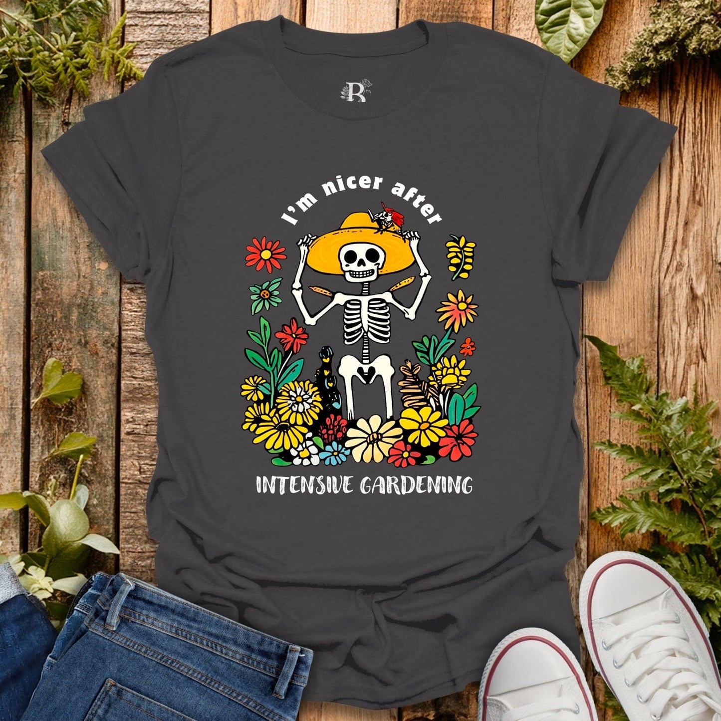 Black t-shirt with skeleton and flowers design on a wooden surface with jeans and shoes.