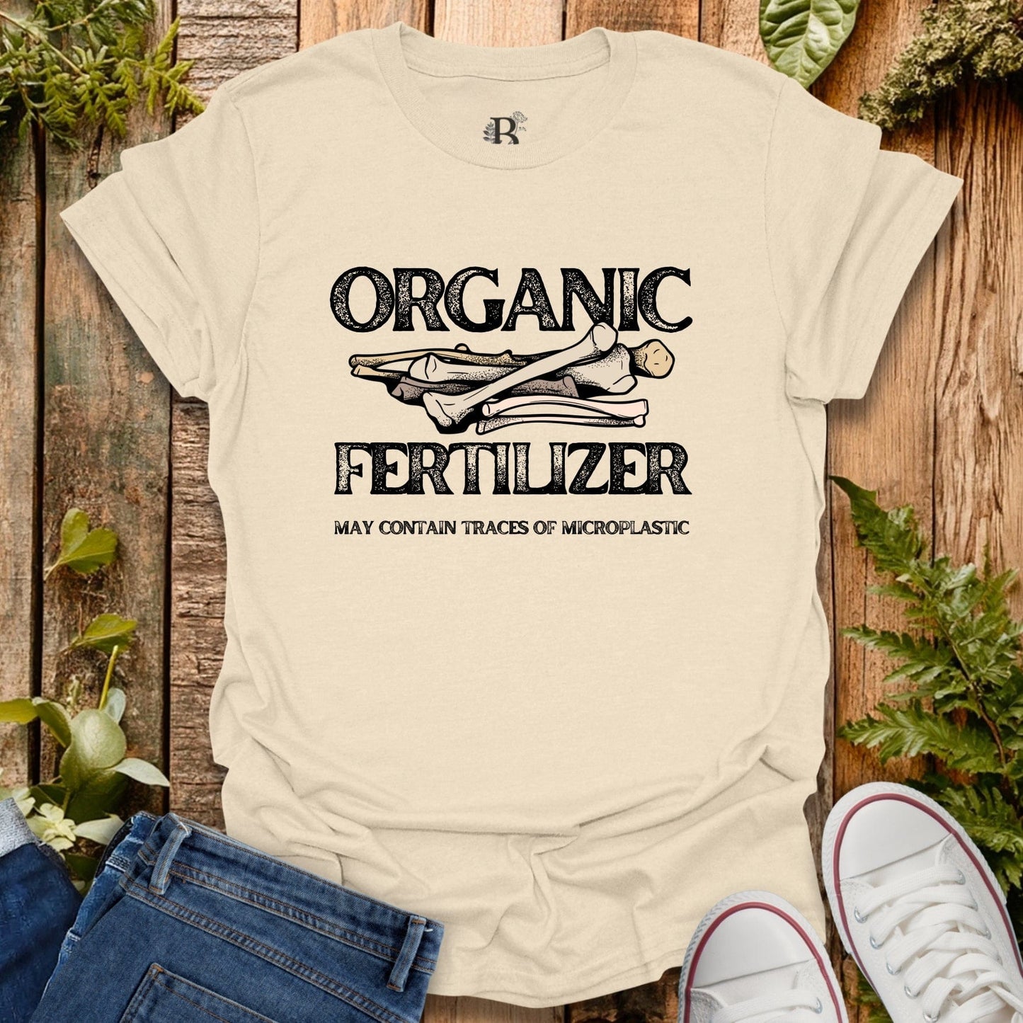 Beige t-shirt with 'Organic Fertilizer' graphic on a wooden background with plants.