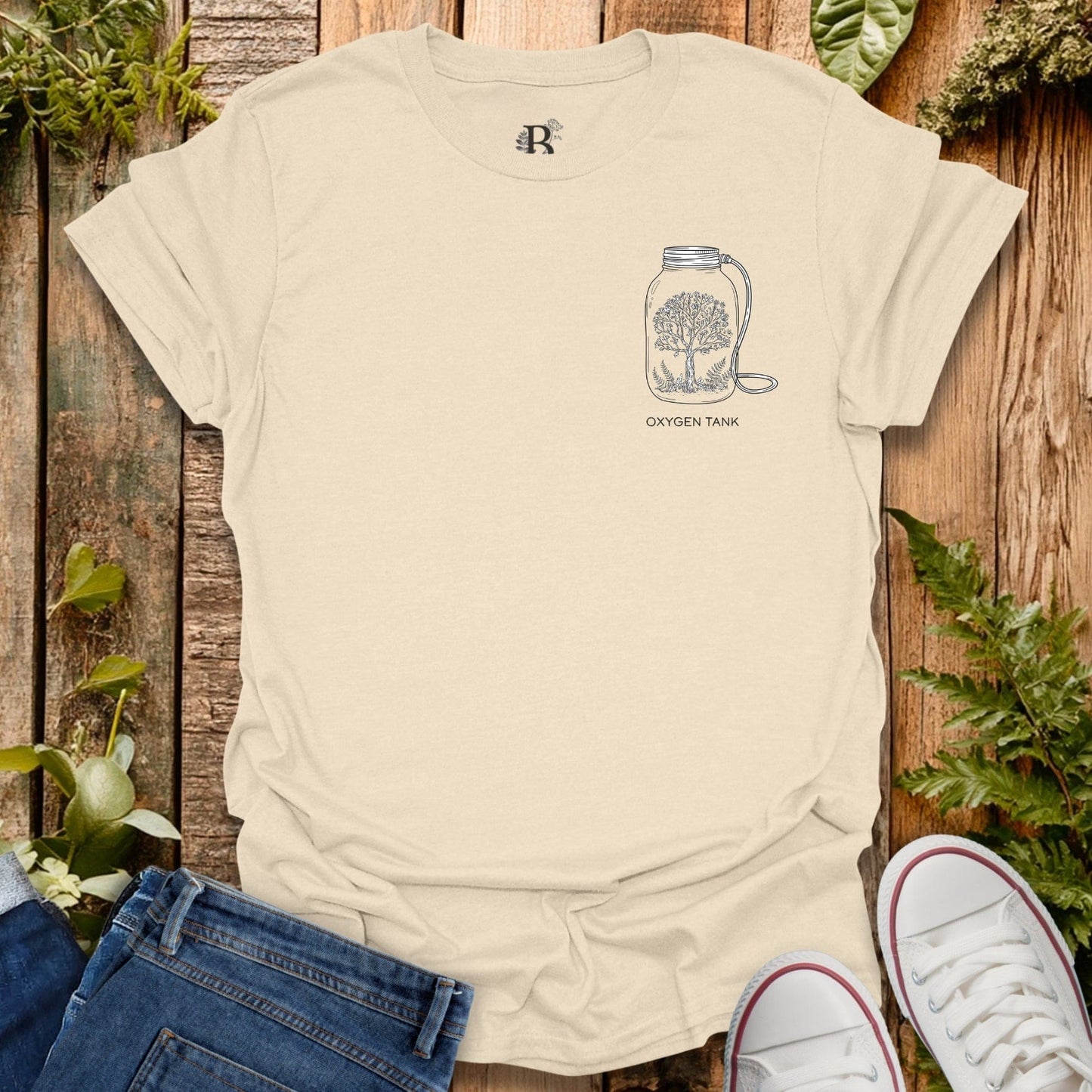 Beige t-shirt with a graphic design on a wooden surface with plants