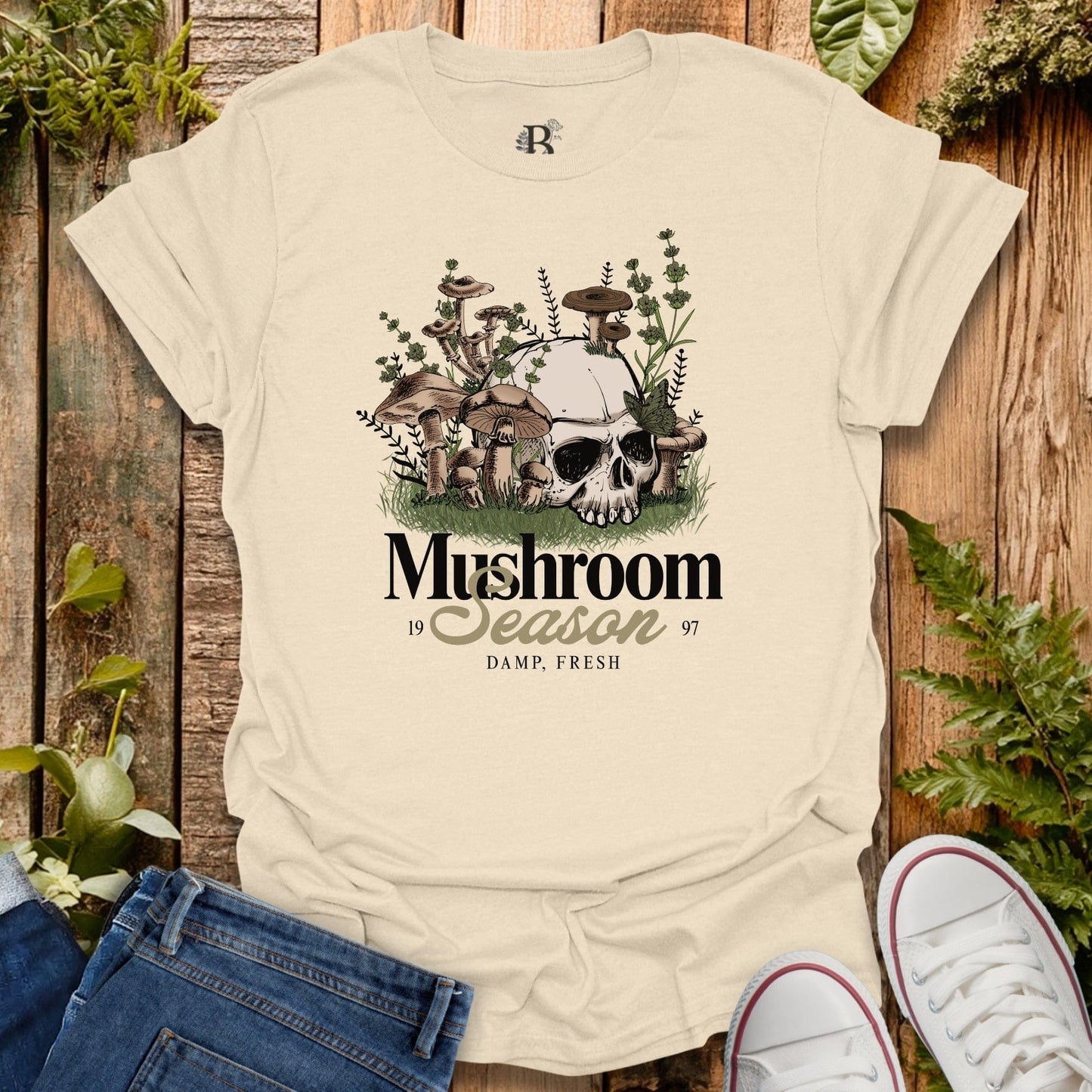Beige t-shirt with mushroom graphic and text on a wooden background