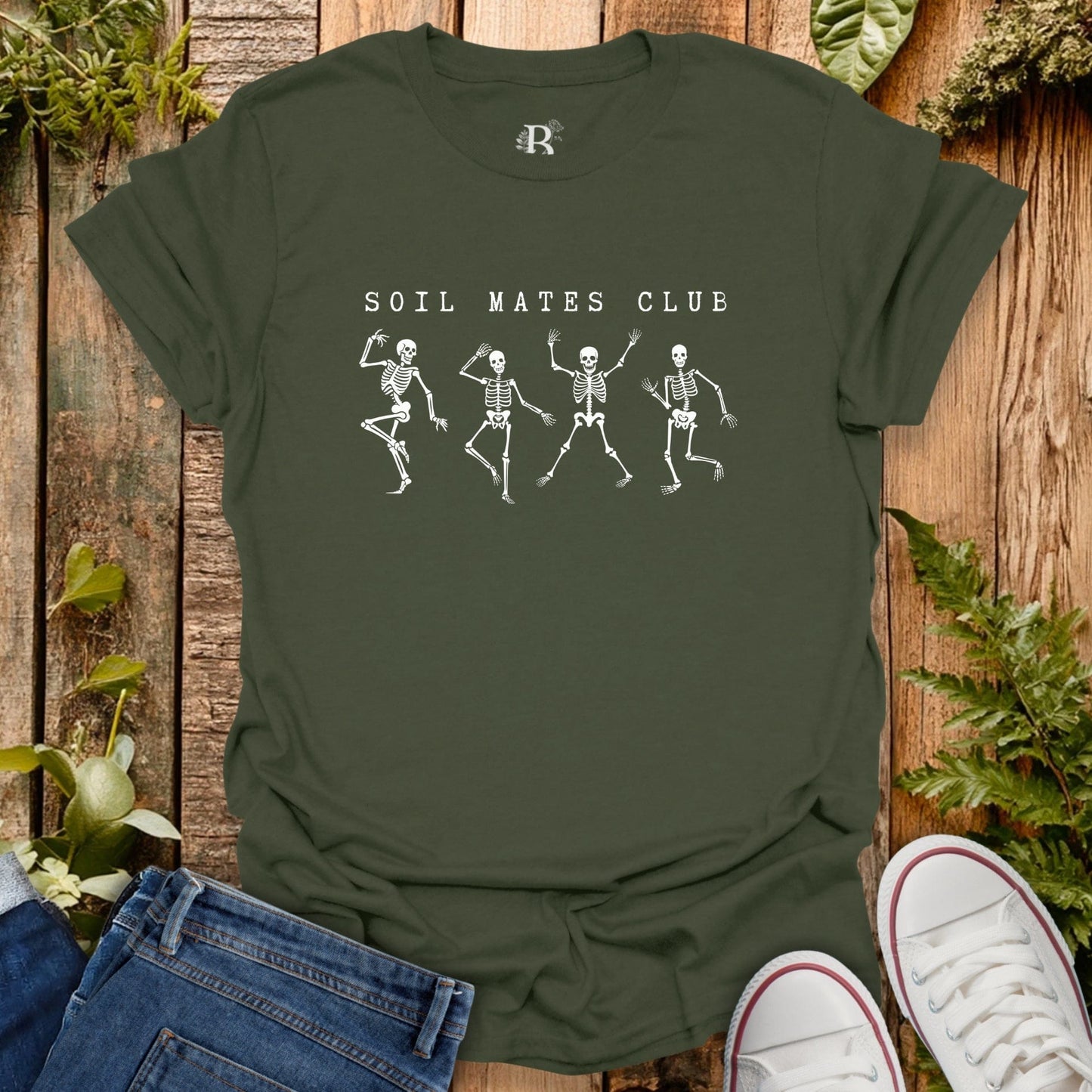Green t-shirt with skeleton design and 'Soil Mates Club' text on a wooden background