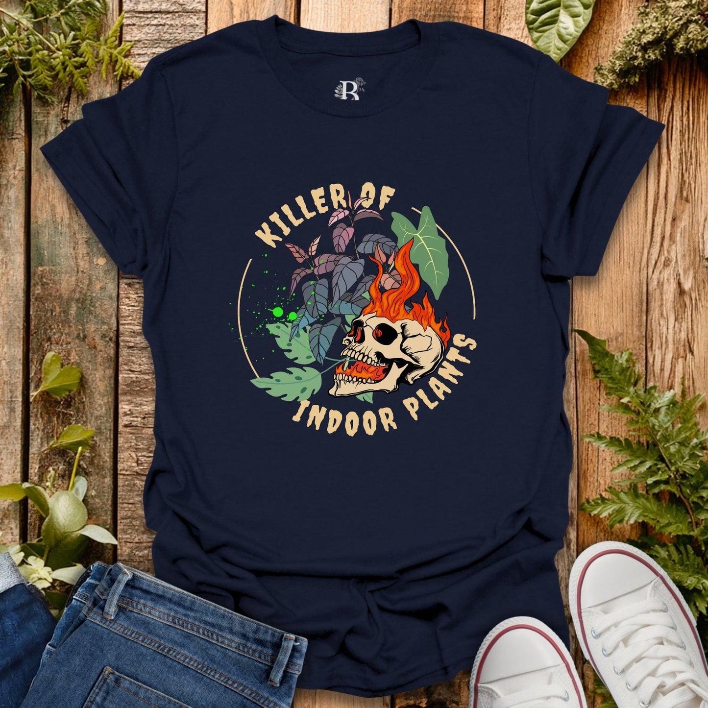Navy blue t-shirt with skull and plant design on a wooden surface with plants around