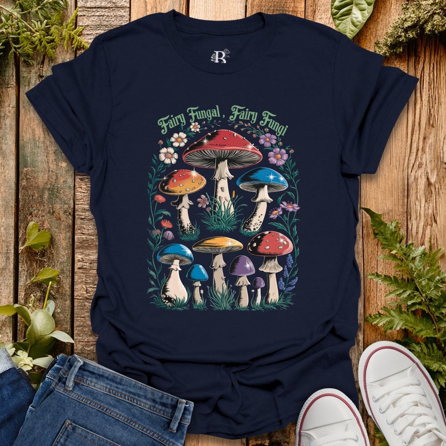 Navy blue t-shirt with colorful mushroom design on a wooden surface with plants.