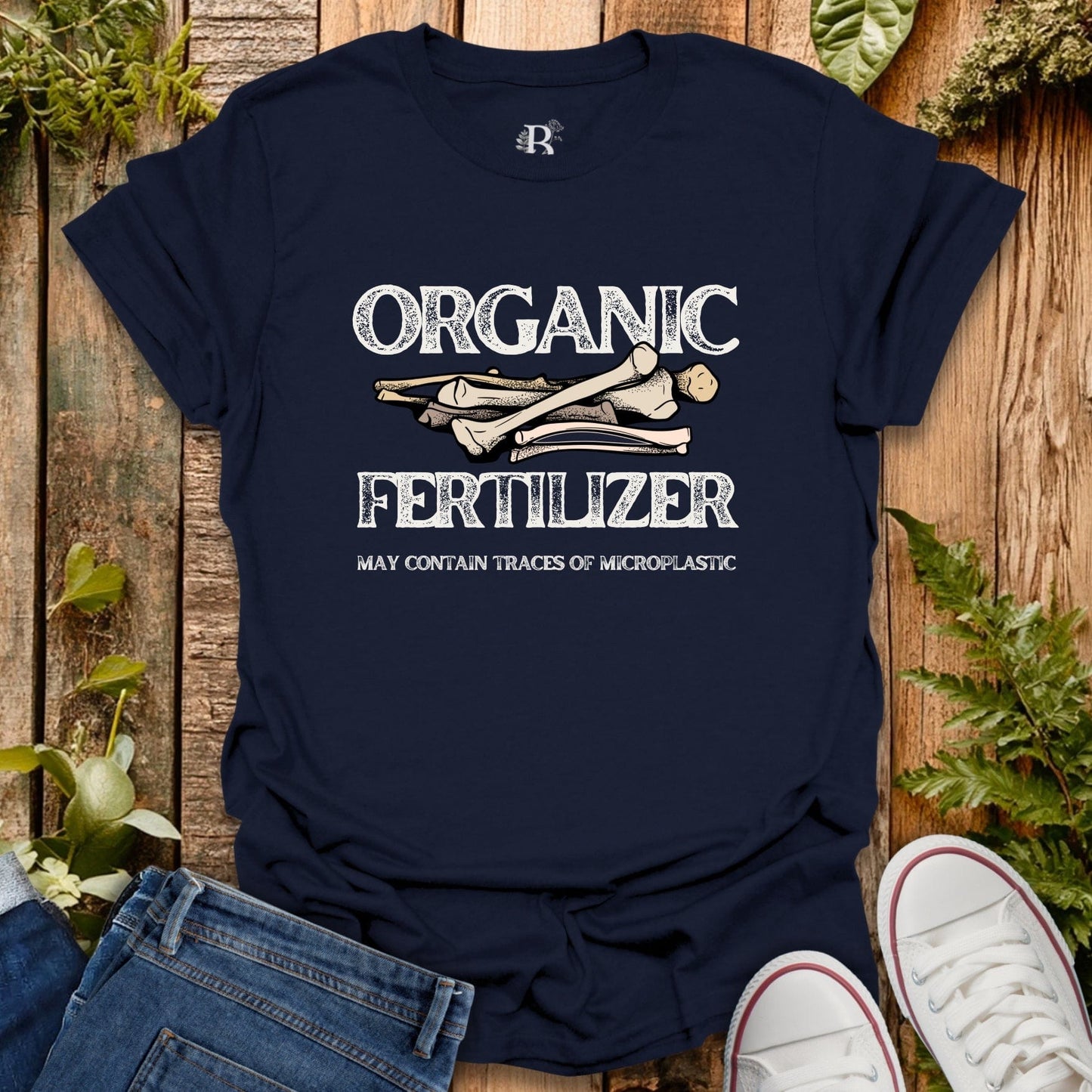 Navy blue t-shirt with 'Organic Fertilizer' graphic on a wooden surface with plants.
