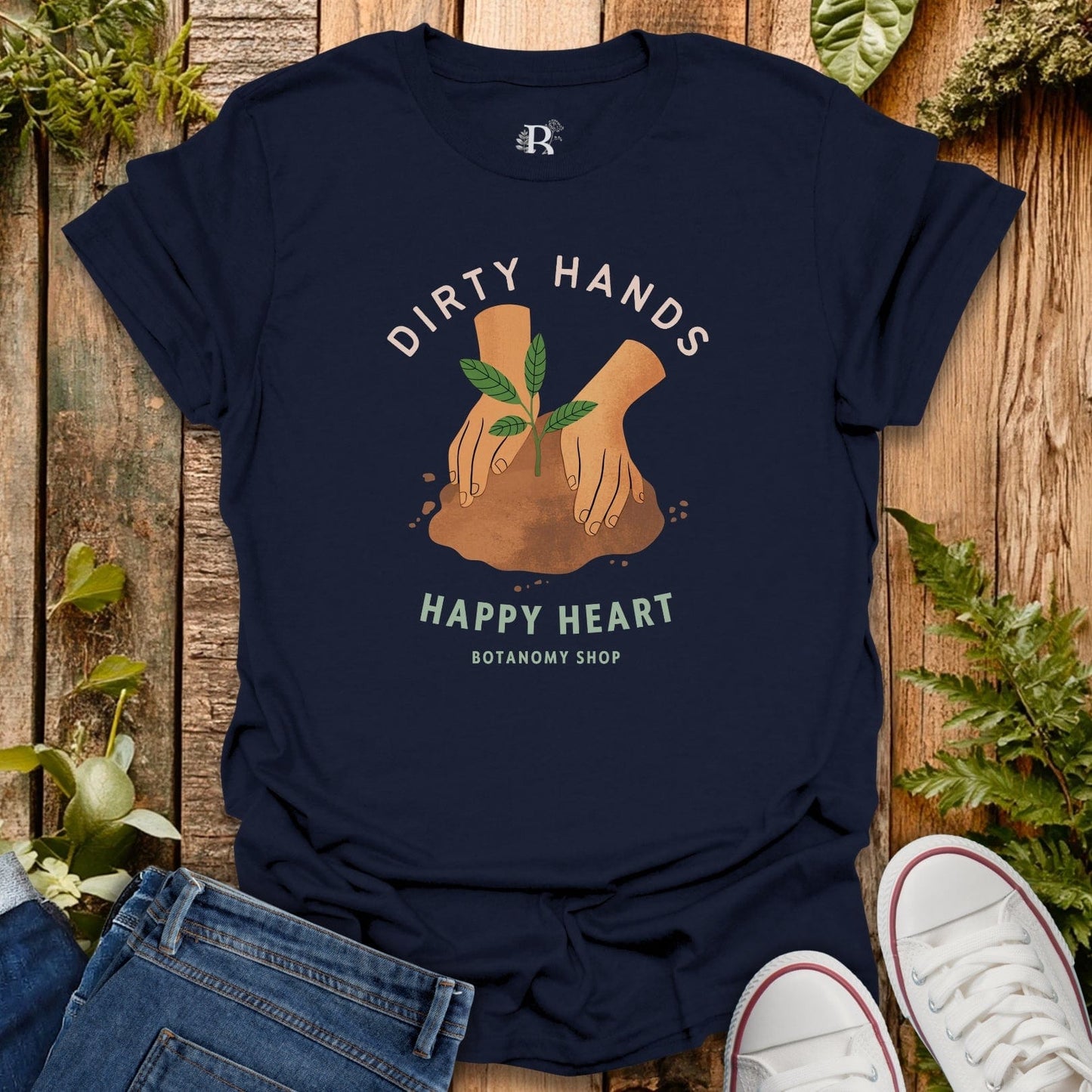 Navy blue t-shirt with 'Dirty Hands Happy Heart' design on a wooden surface with plants.