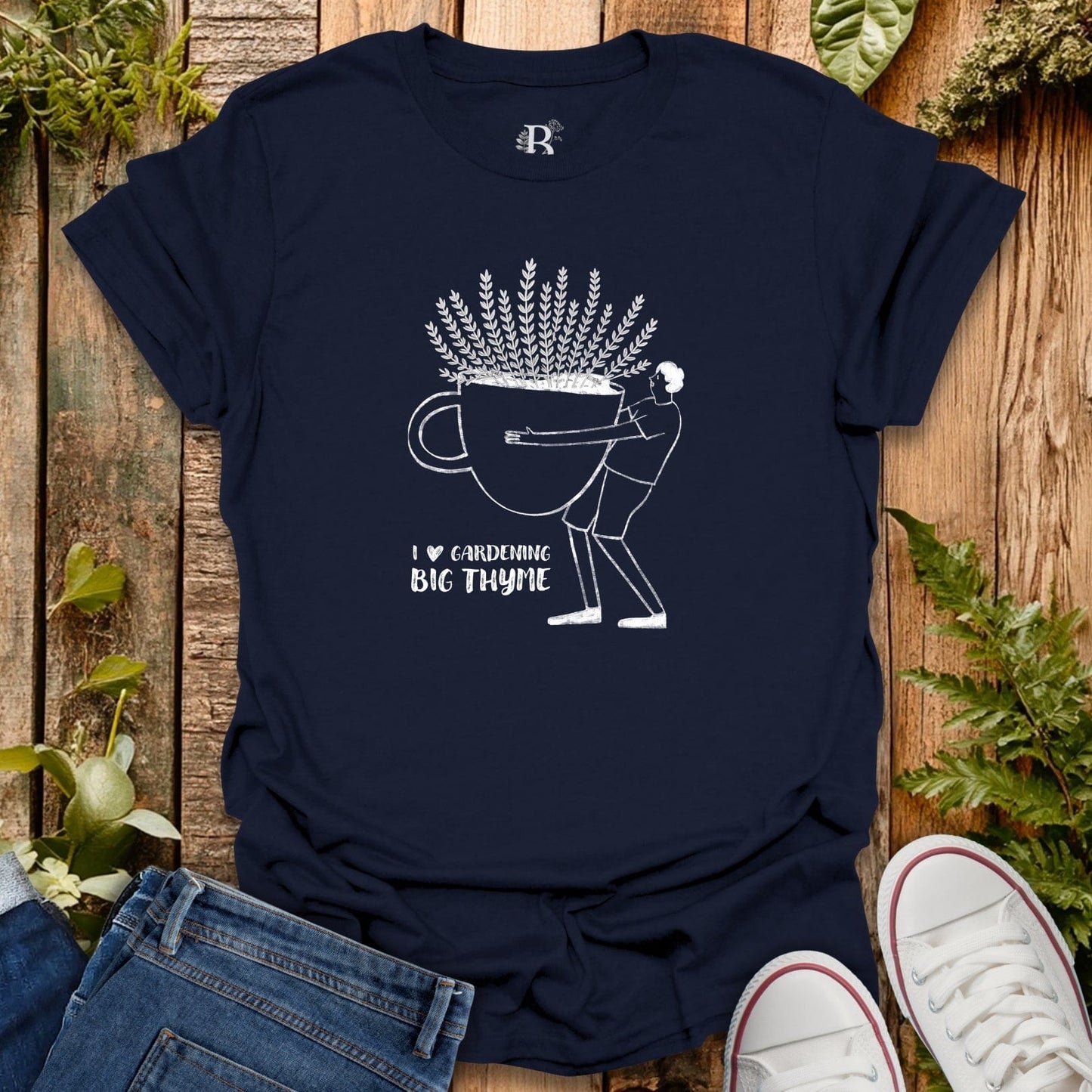 Navy blue t-shirt with white graphic design on a wooden surface with plants.