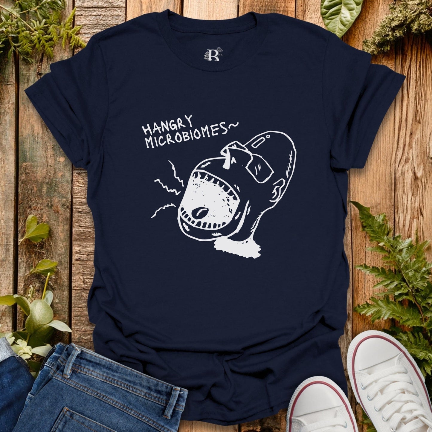 Navy blue t-shirt with a graphic design and text on a wooden surface with plants.