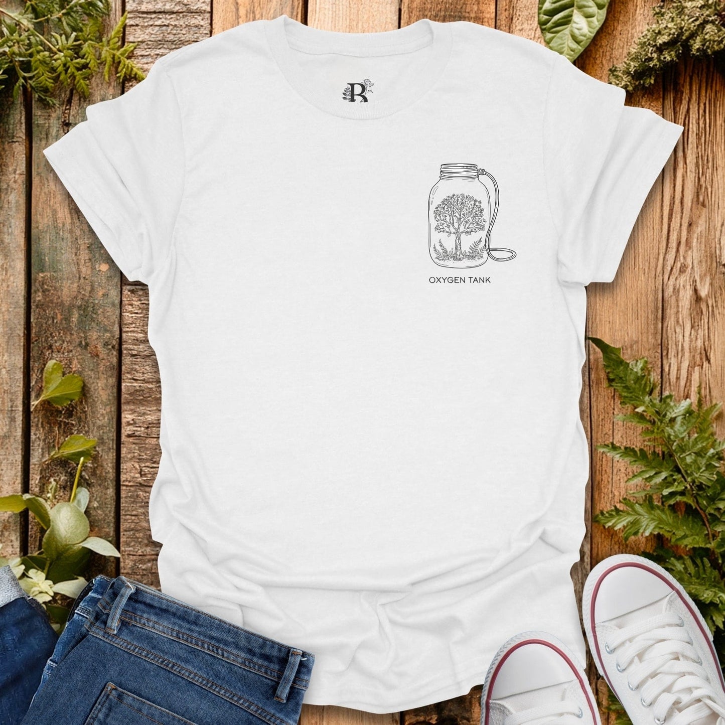 White t-shirt with a graphic design on a wooden surface with plants