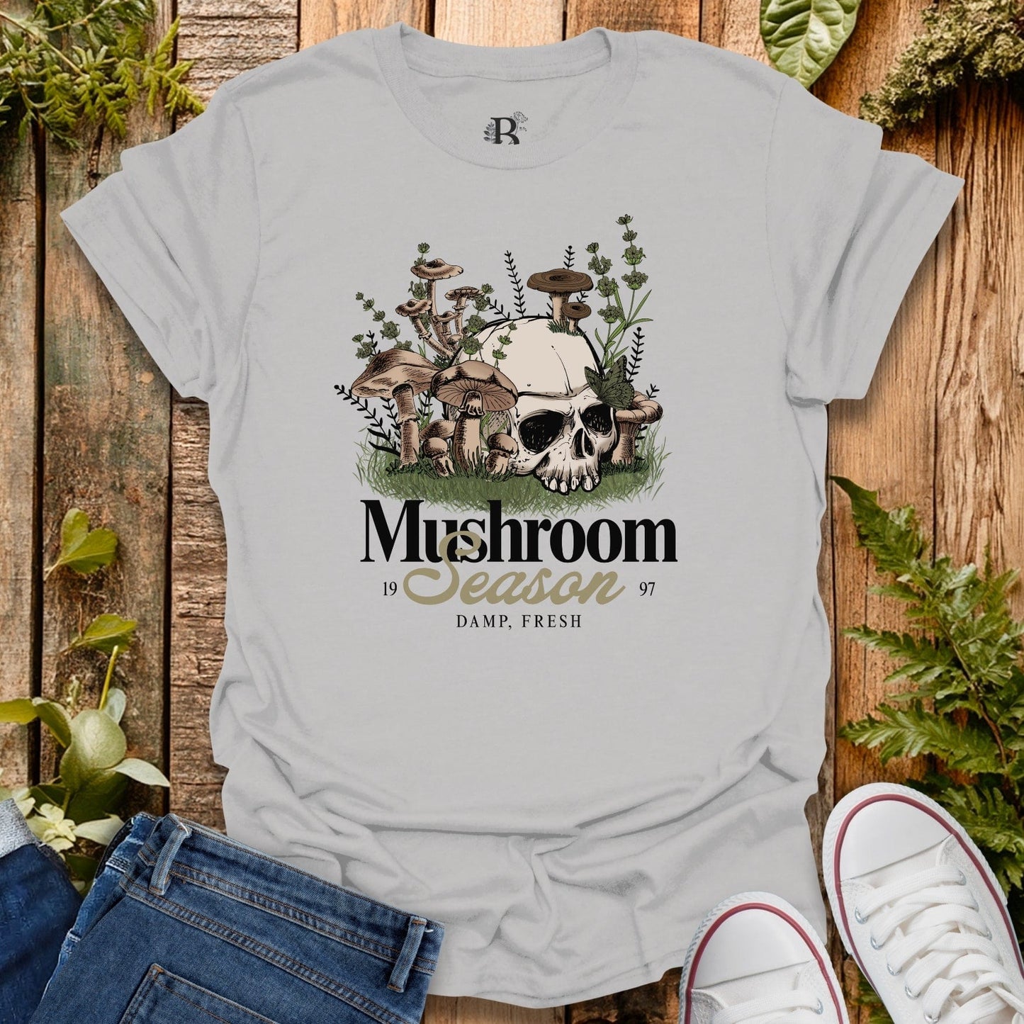 Gray t-shirt with mushroom graphic and text on a wooden background