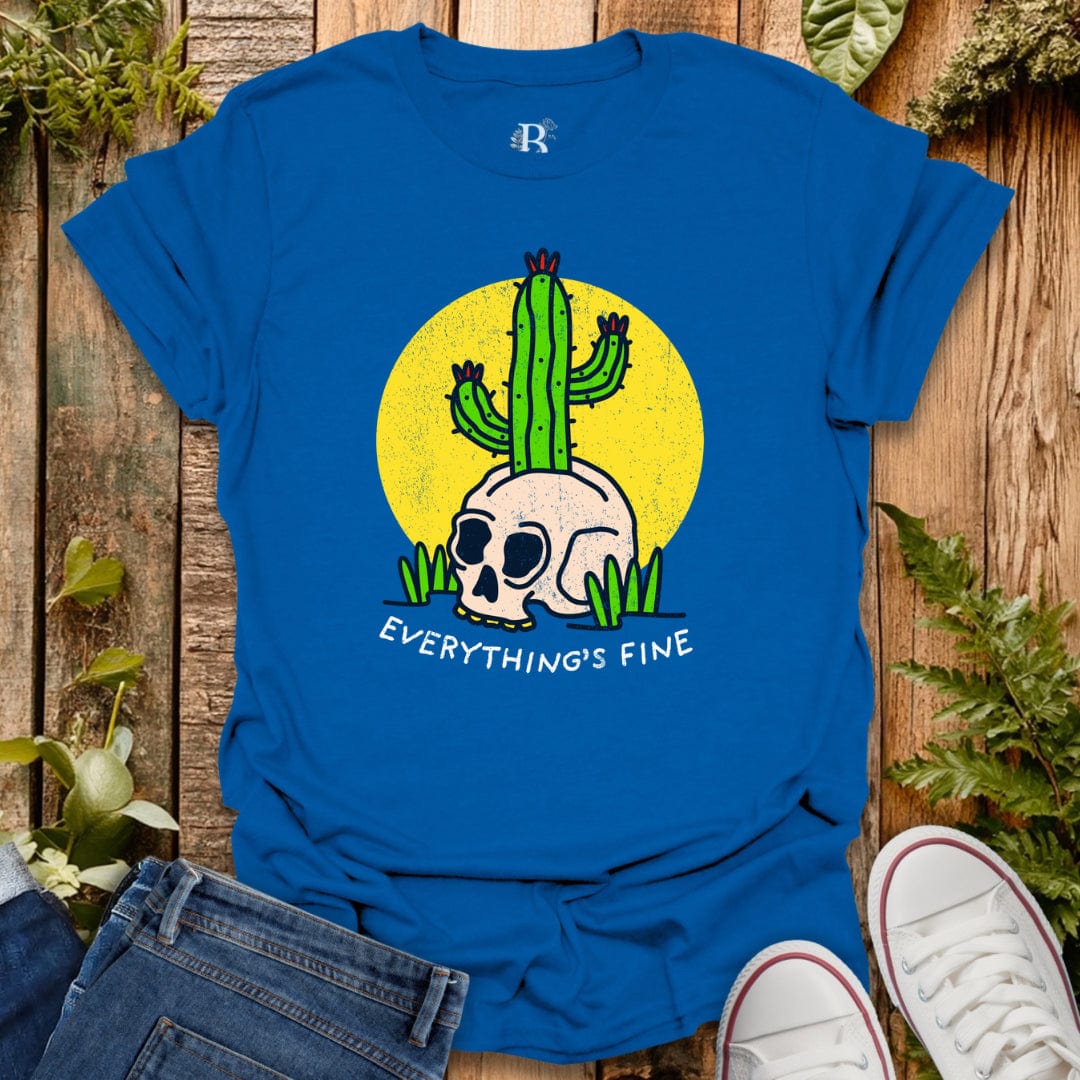 Blue t-shirt with a skull and cactus design and 'Everything's Fine' text on a wooden surface.
