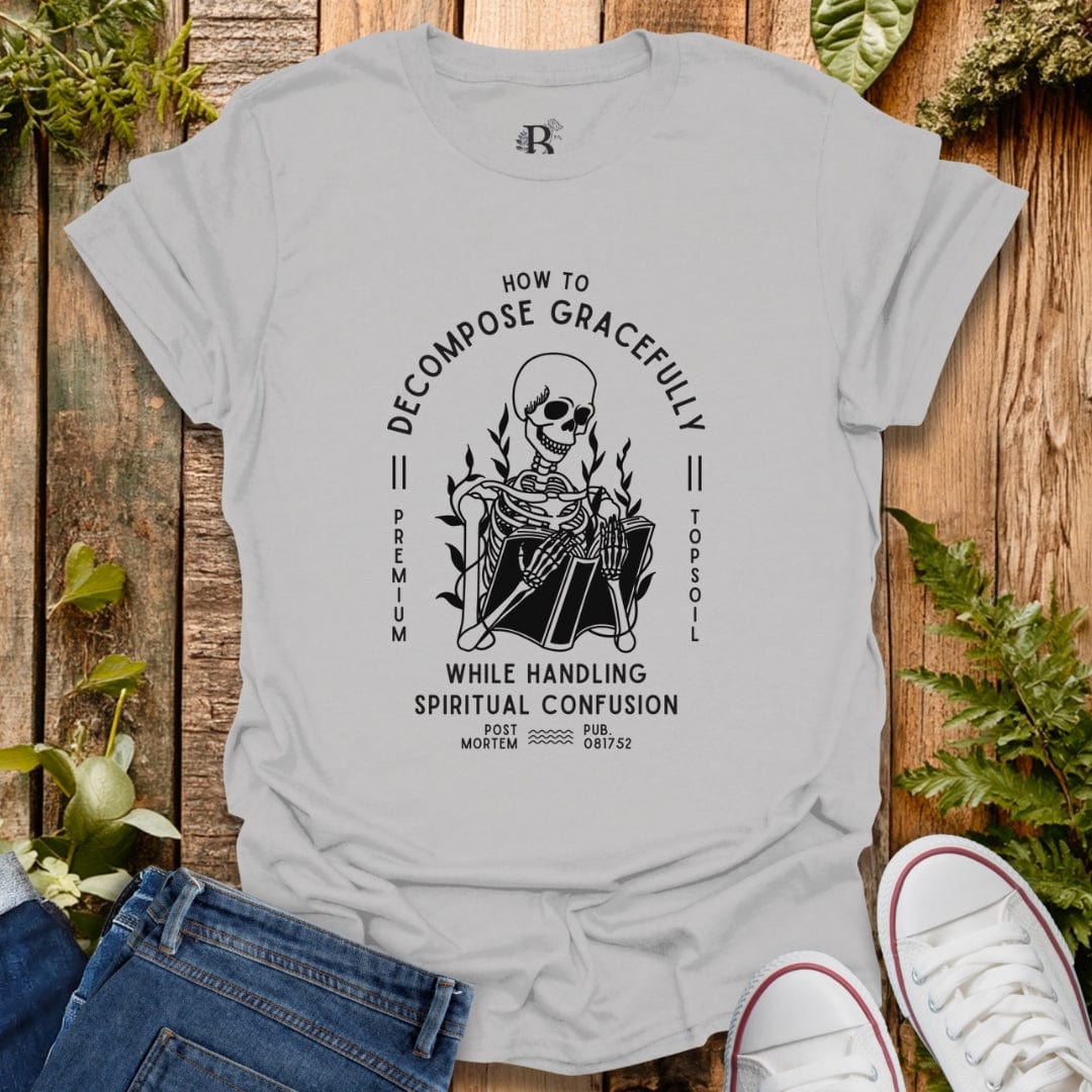 Gray t-shirt with a black graphic design on a wooden surface with plants.