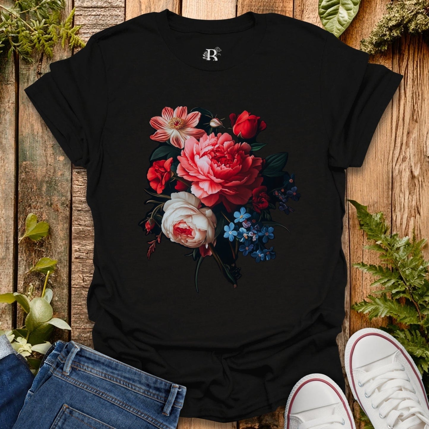 Black t-shirt with floral design on a wooden surface with plants around