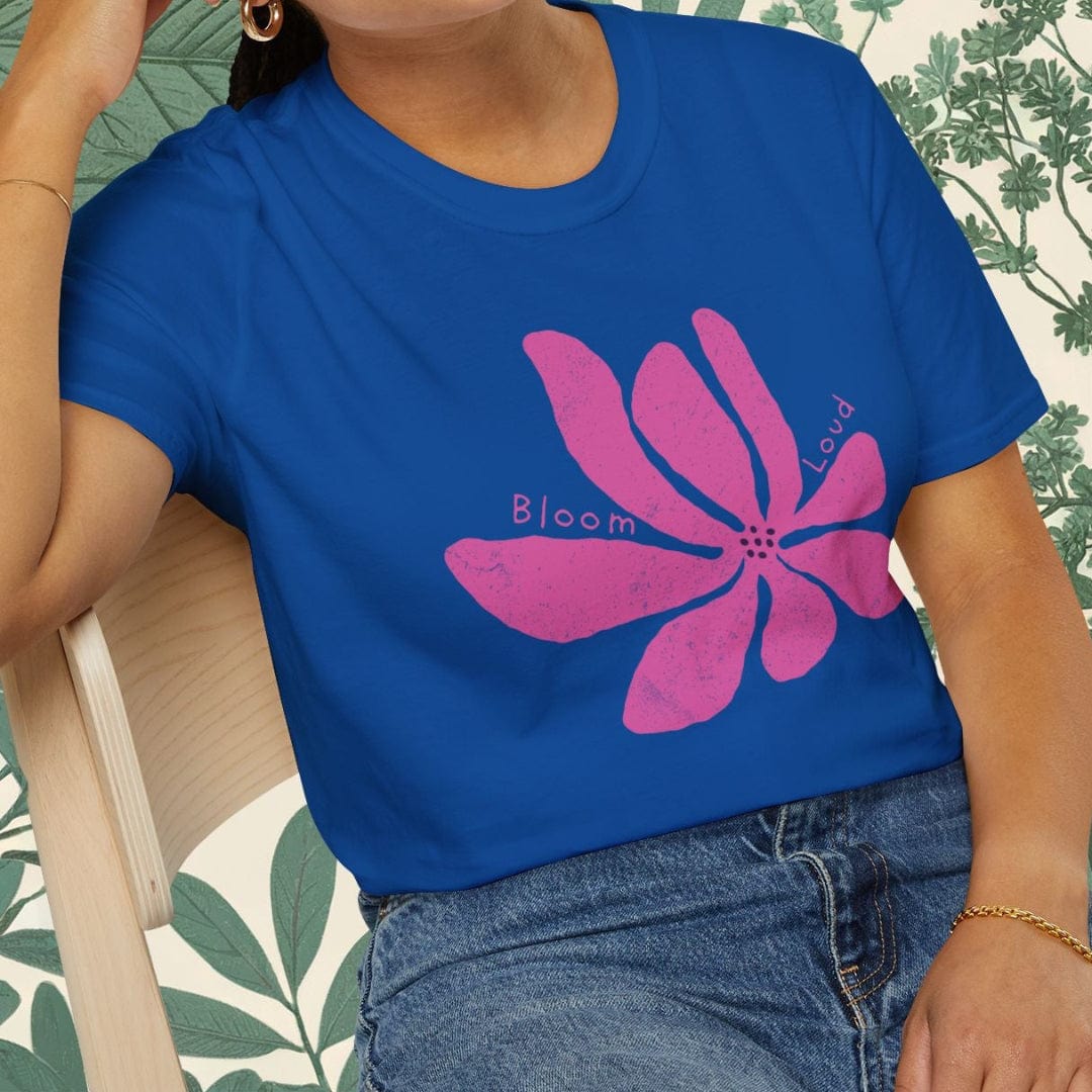 Woman wearing a blue t-shirt with a pink flower design, sitting on a chair.