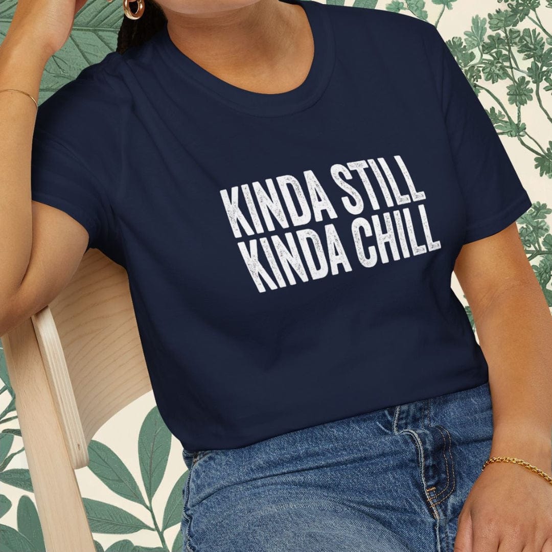 Person wearing a navy blue t-shirt with 'KINDA STILL KINDA CHILL' text, sitting on a chair.