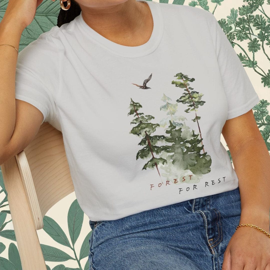 Woman wearing a white t-shirt with nature-themed design and blue jeans, sitting on a chair.