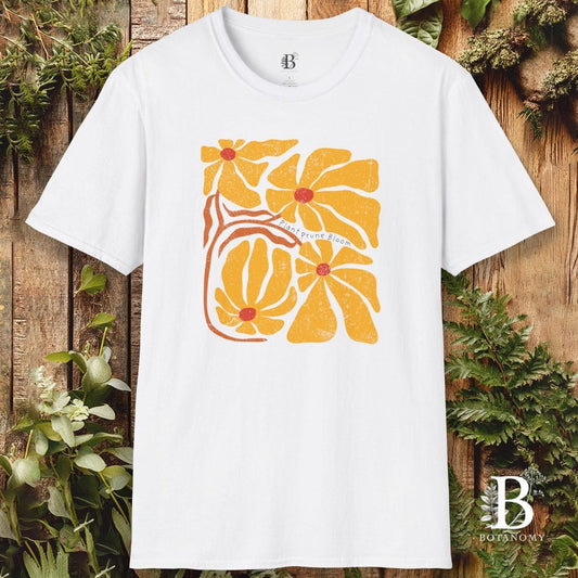 White t-shirt with yellow floral design on a wooden background