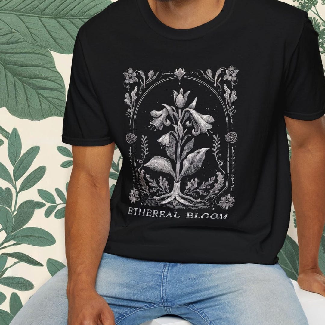 Man wearing a black t-shirt with a floral design and text, sitting on a white stool.