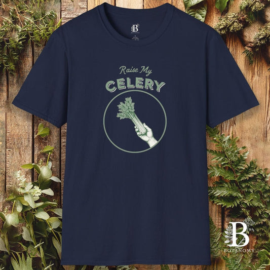 Navy blue t-shirt with 'Raise My Celery' graphic design on a wooden background with celery plants.