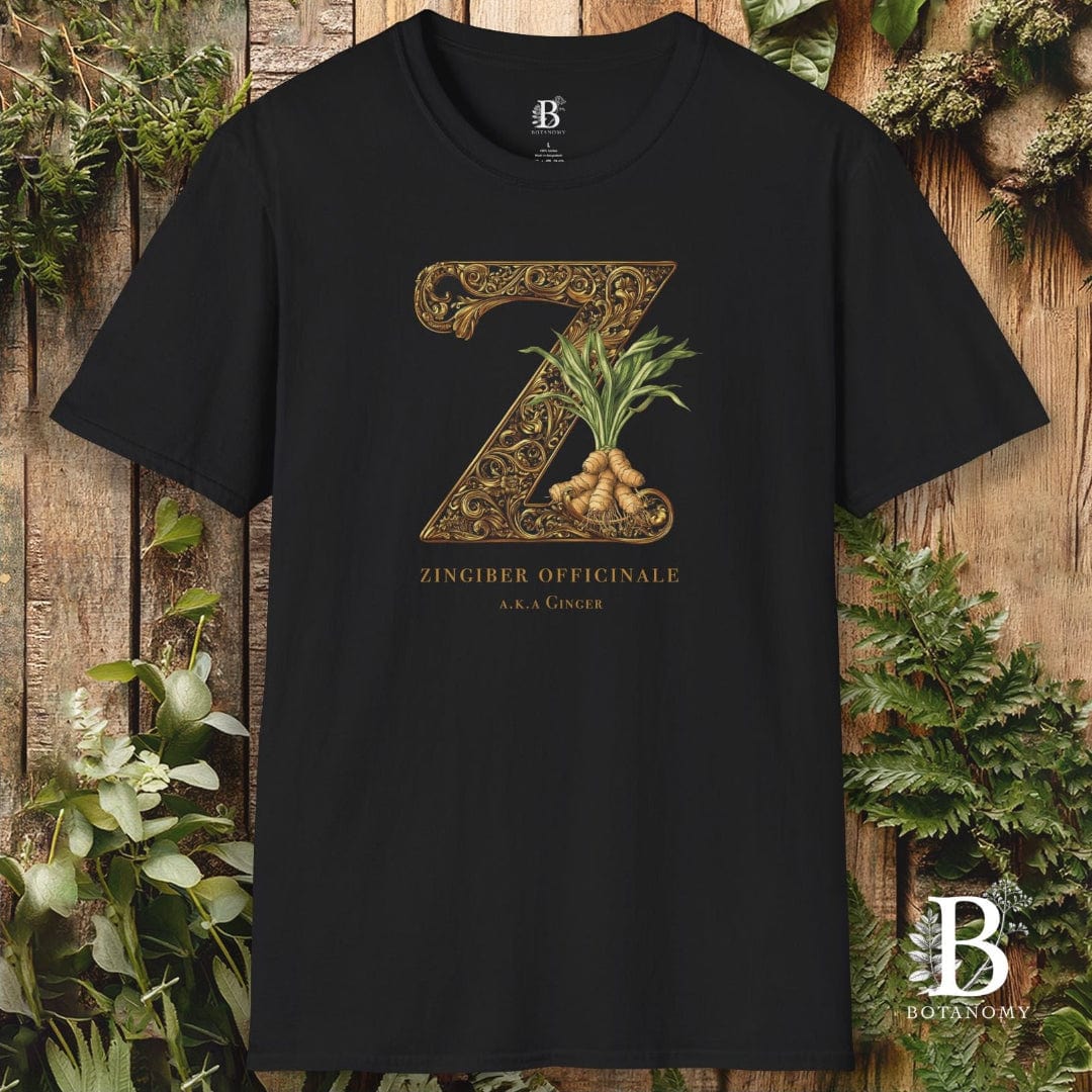 Black t-shirt with a gold 'Z' design featuring a plant, on a wooden background with greenery.