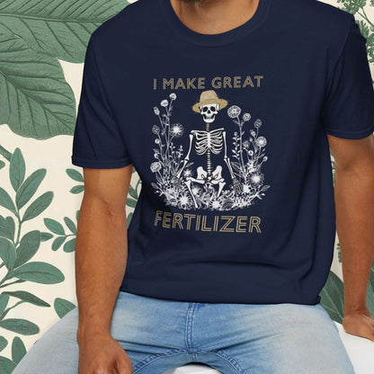 Man wearing a navy blue t-shirt with a skeleton graphic and text, sitting on a white stool with a green leafy background.