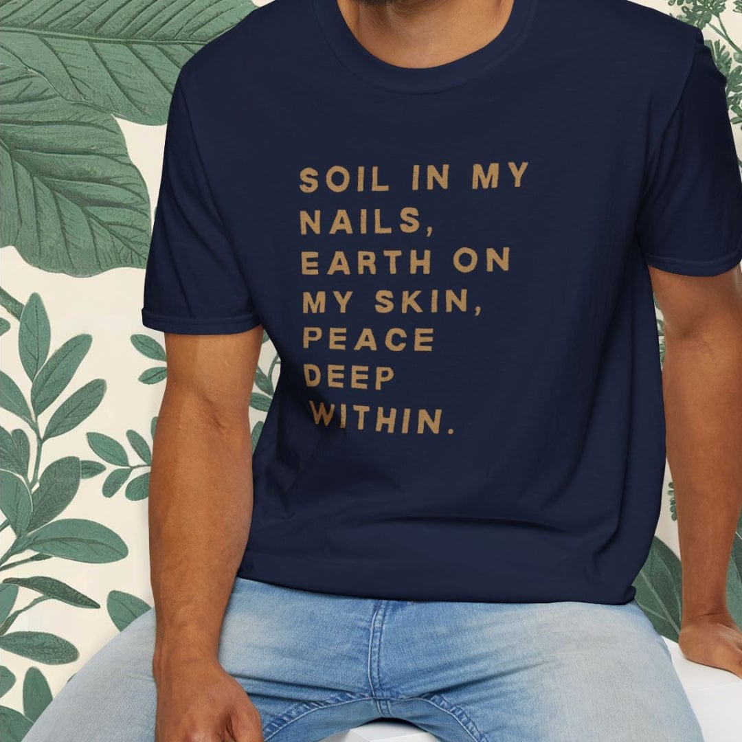 Man wearing a navy blue t-shirt with text, sitting on a white stool with a green leafy background.