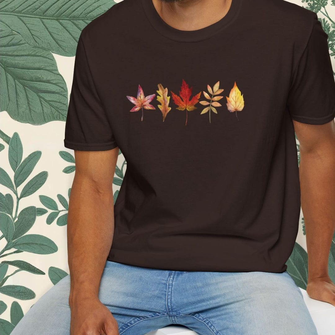 Man wearing a black t-shirt with colorful leaf design sitting on a white stool against a white background.