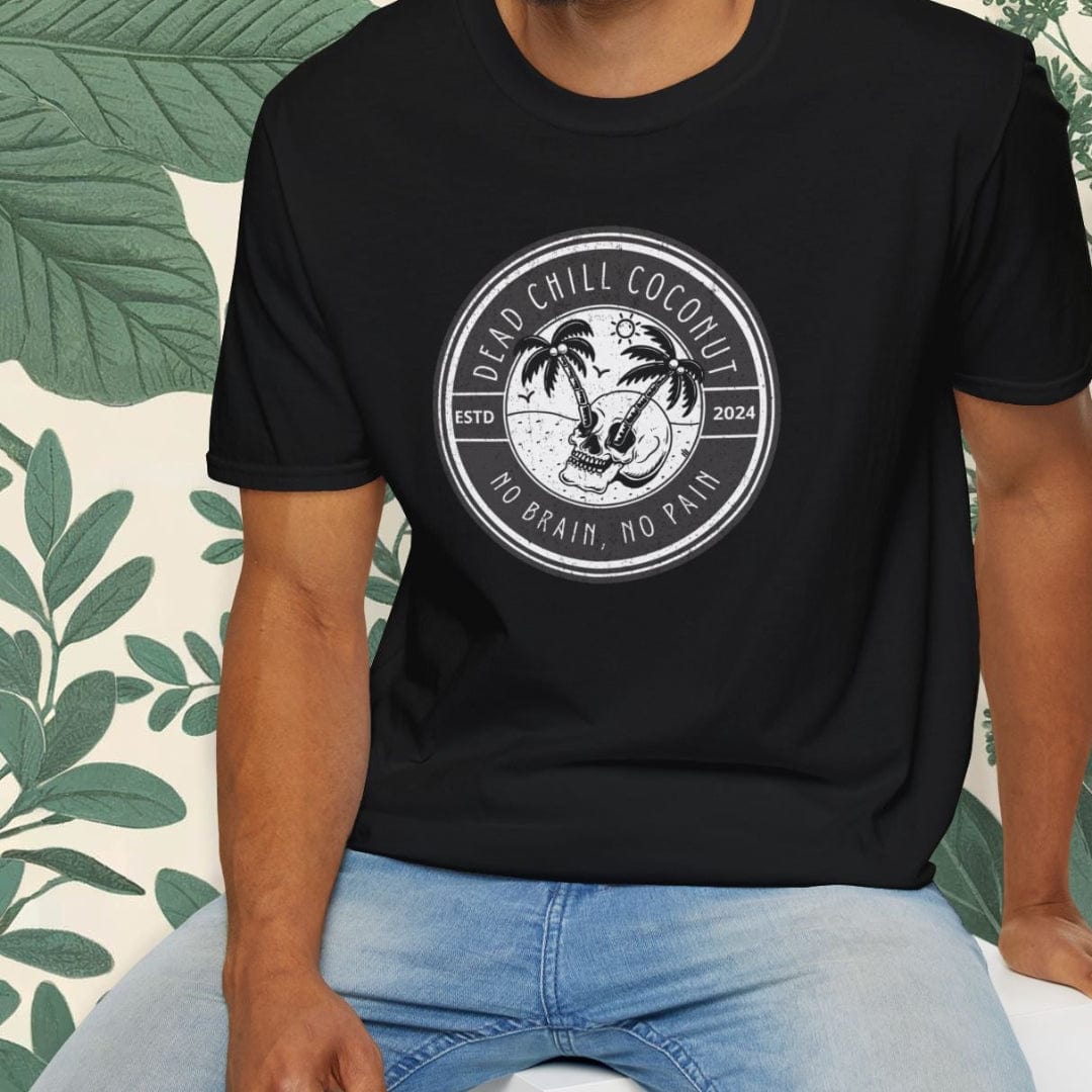 Man wearing a black t-shirt with a palm tree design, sitting on a white stool with a green leafy background.