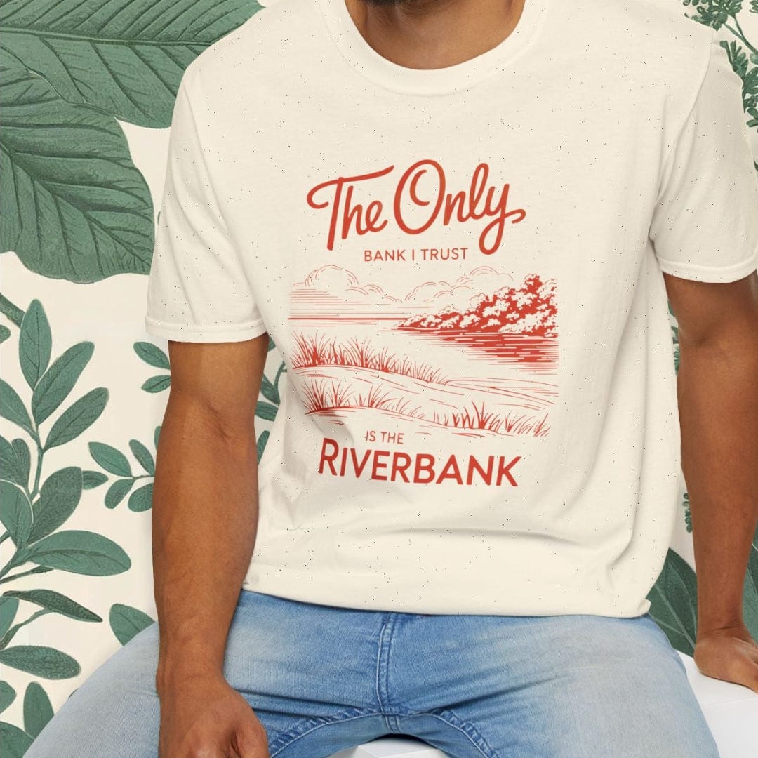 Man wearing a white t-shirt with red text and graphics, sitting on a white stool against a green leafy background.