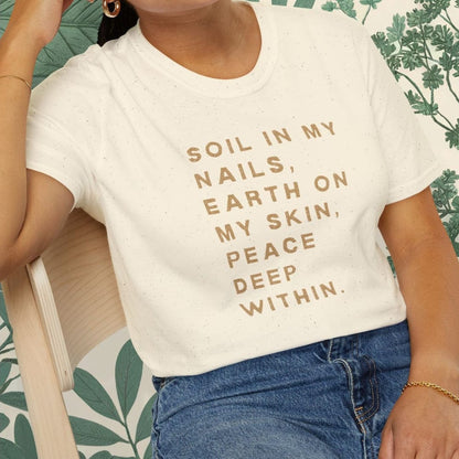 Woman wearing a white t-shirt with text, sitting on a chair with a green leafy background