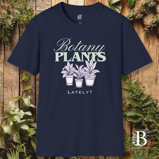 Navy blue t-shirt with 'Botany Plants Lately?' design on a wooden background with plants.