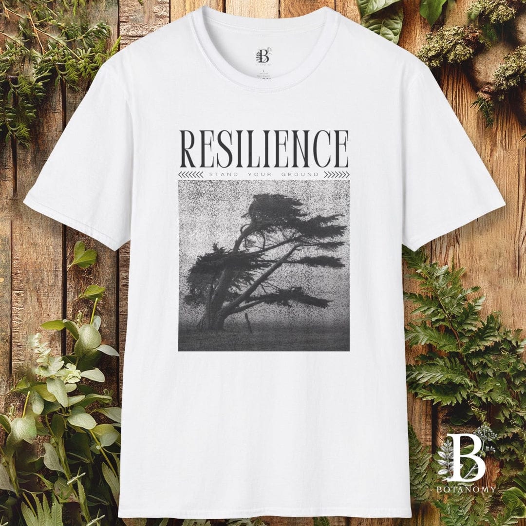 White t-shirt with 'RESILIENCE' graphic and tree silhouette on a wooden background