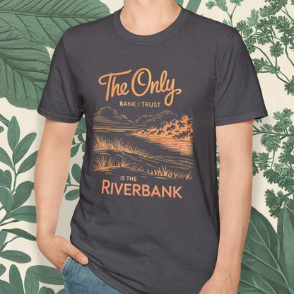 Man wearing a t-shirt with a scenic design and text, standing against a leafy background