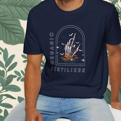 Man wearing a navy blue t-shirt with a graphic design, sitting on a white stool with a green leafy background.