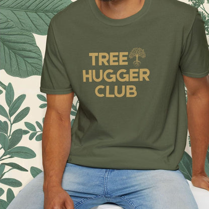 Man wearing a green t-shirt with 'Tree Hugger Club' text, sitting on a white stool with a leafy background.