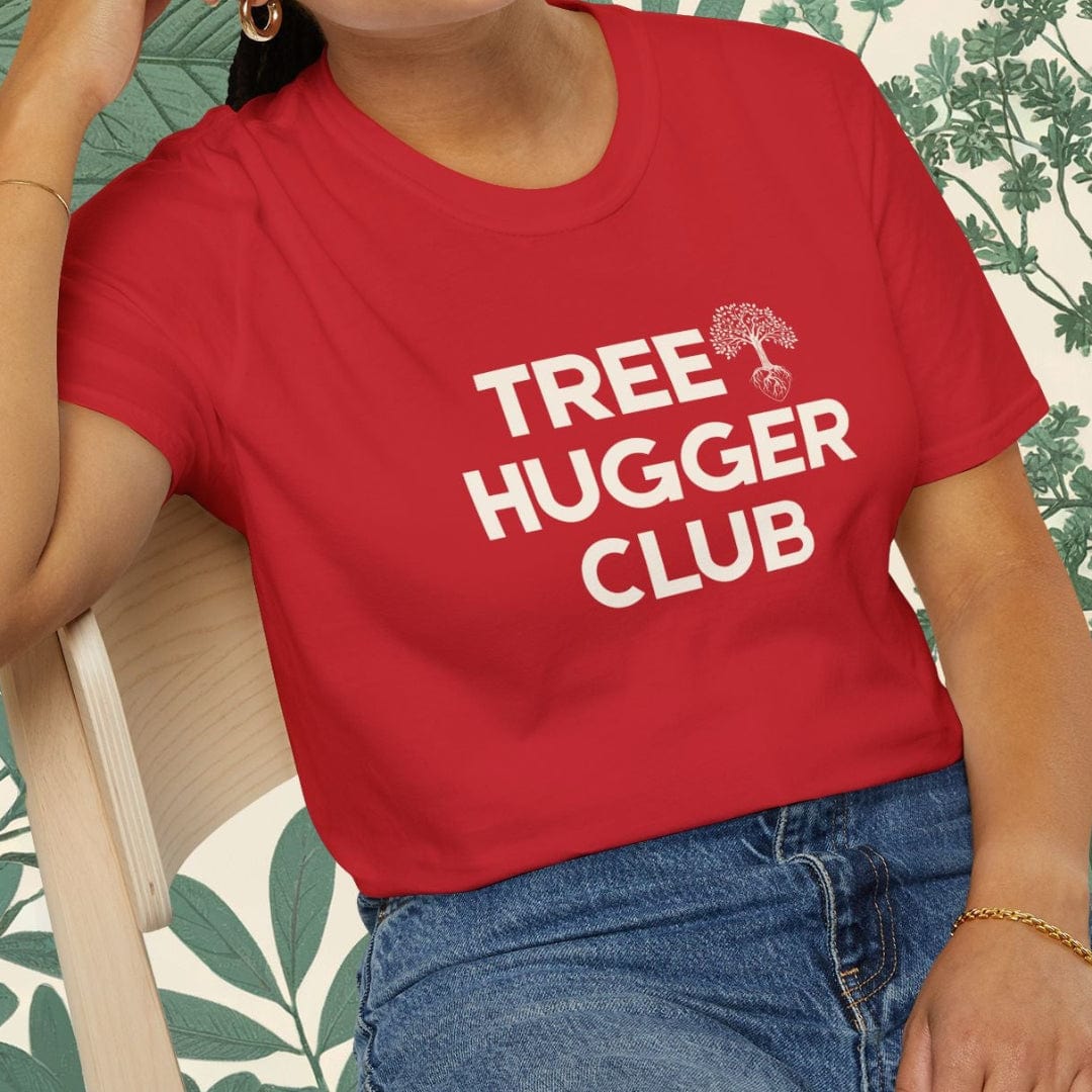 Person wearing a red 'Tree Hugger Club' t-shirt sitting on a chair with a leafy background.