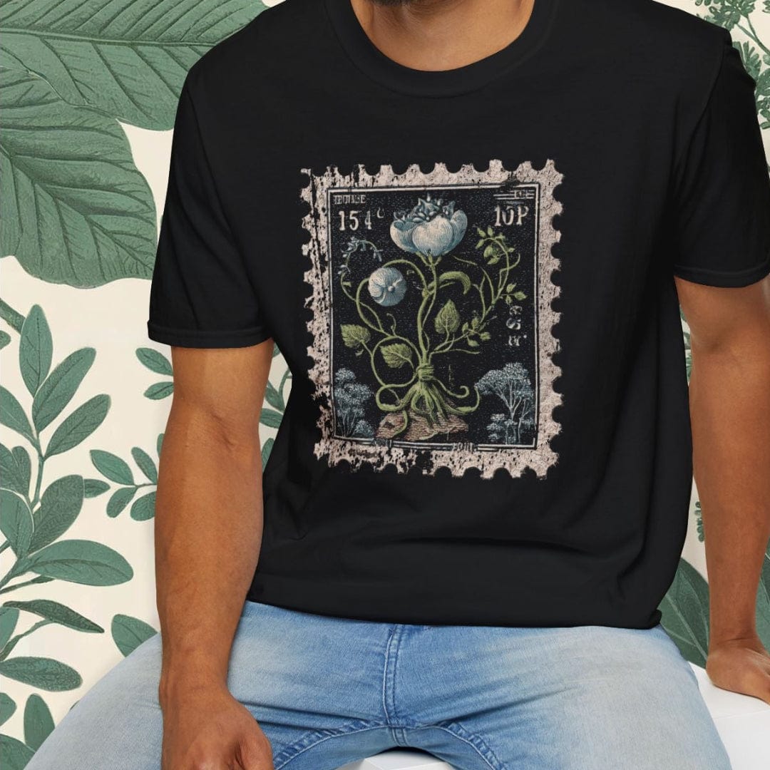 Man wearing a black t-shirt with a floral design, sitting on a white stool against a white background.