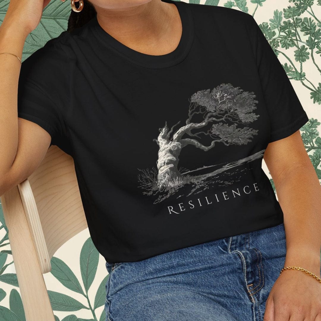 Person wearing a white t-shirt with a graphic design and text, standing in front of a leafy background